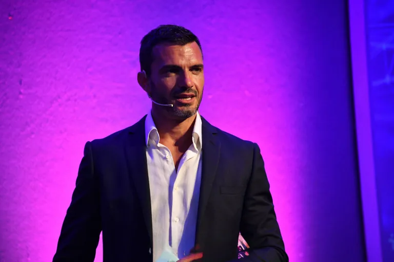 Nicola Nic Donati mentre parla al pubblico durante un evento dal vivo, con microfono ad archetto