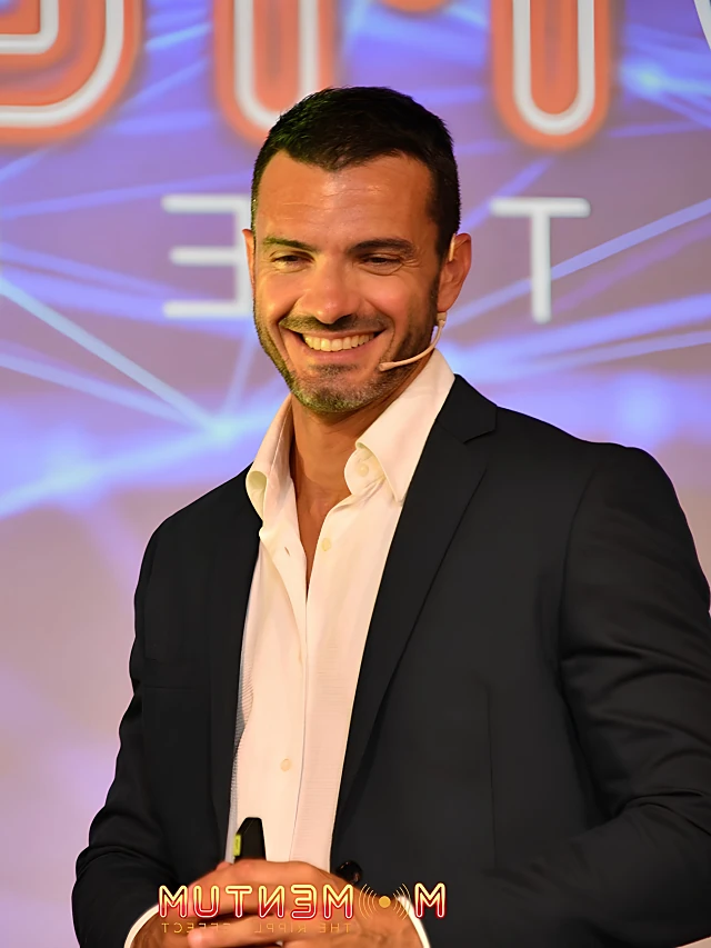 Nicola Nic Donati sorridente, con giacca scura e microfono ad archetto, durante un intervento pubblico